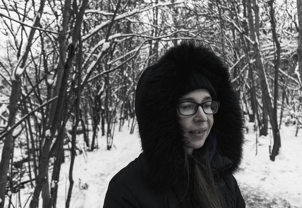 Girl wearing glasses and parka in forest in winter