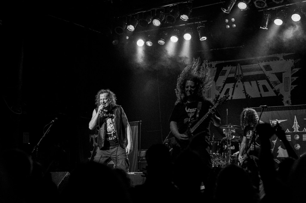 Black-and-white concert photo of heavy metal singer wearing a Motörhead shirt and leather vest.