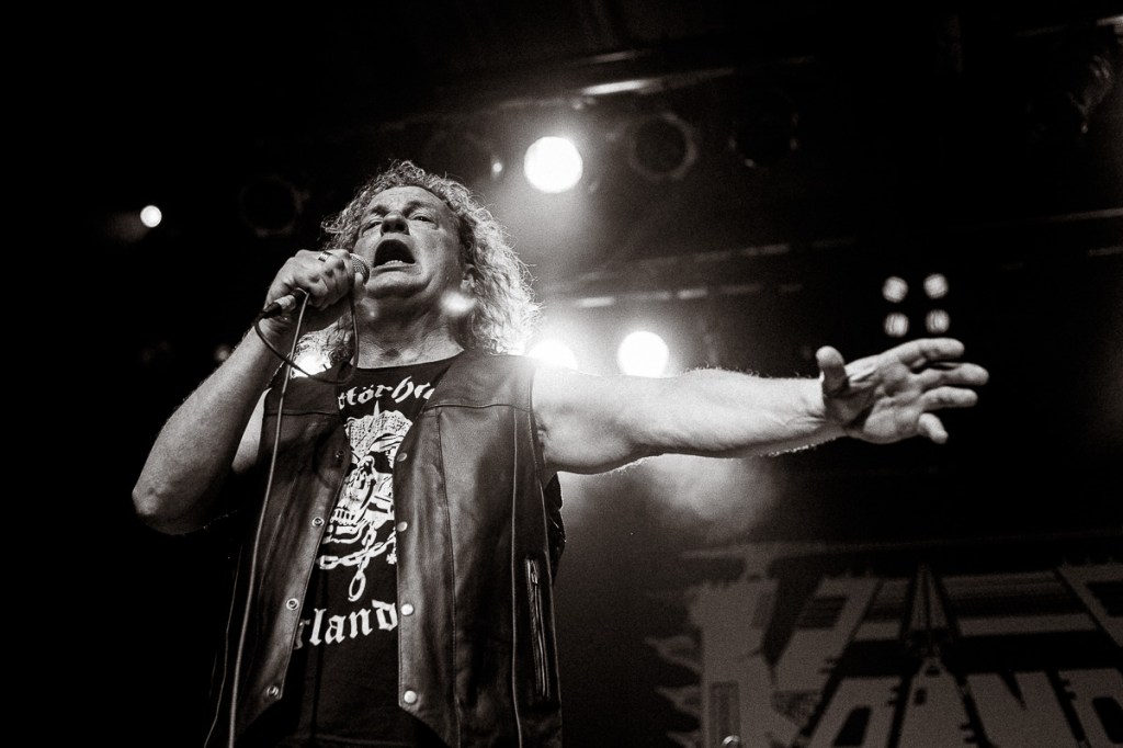 Black-and-white concert photo of heavy metal singer wearing a Motörhead shirt and leather vest.