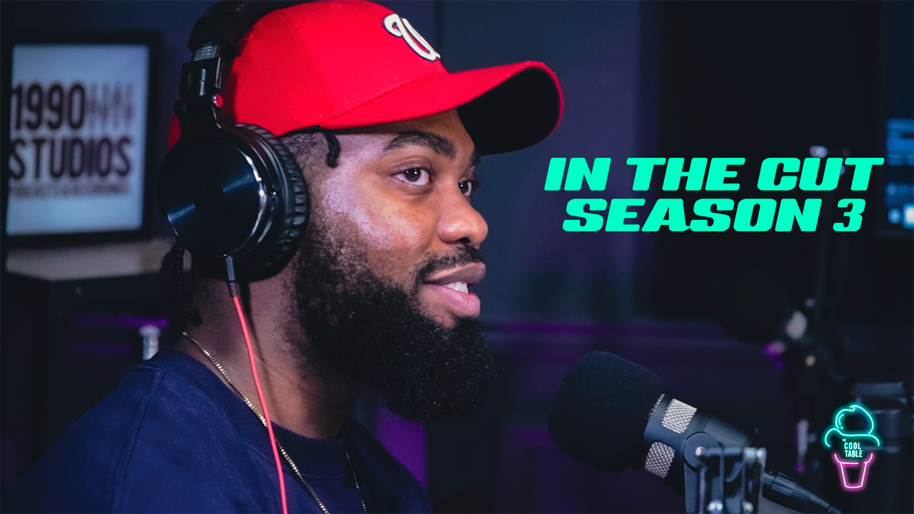 Black podcaster in studio wearing red baseball cap and headphones