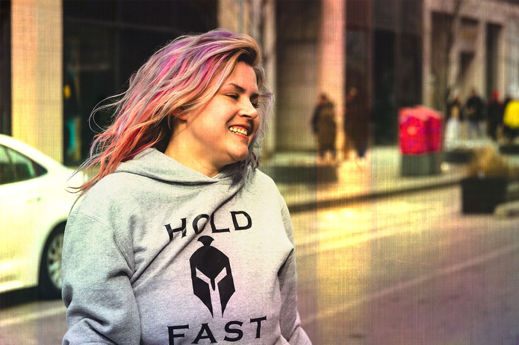 A smiling woman with blonde, pink and purple hair wearing a “Hold Fast” hoodie on Bloor St. © Andy Lee, 2022. realandylee.com