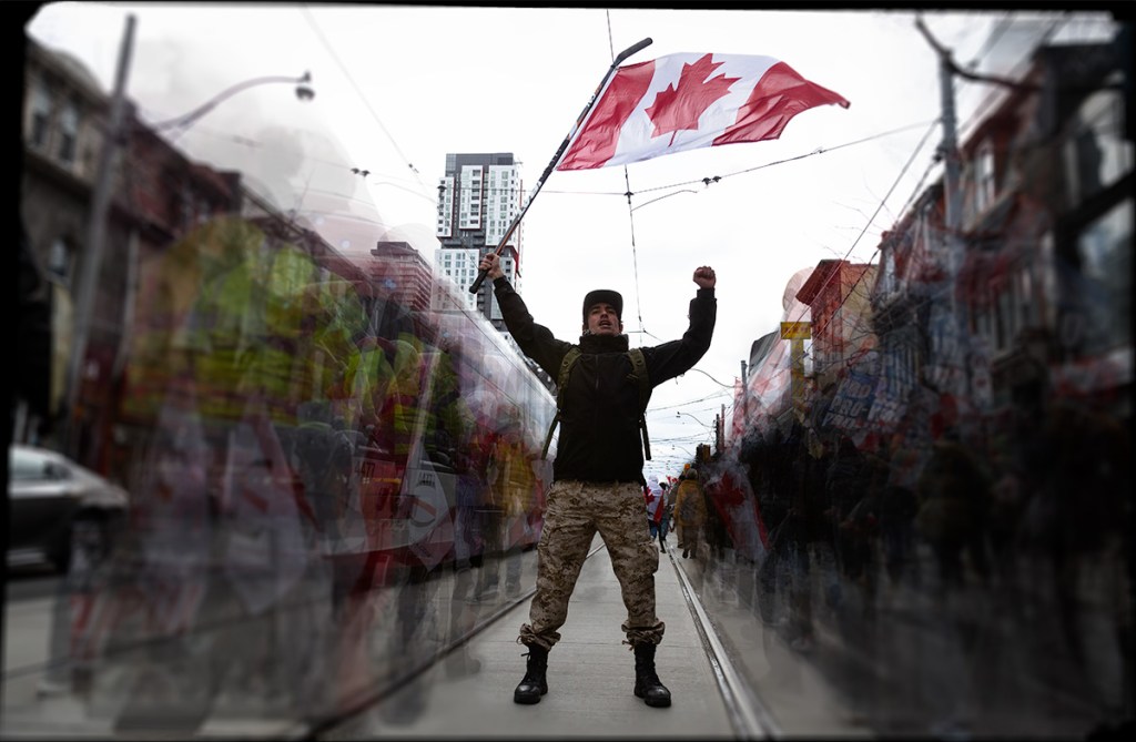 A man waving a Canada flag on the street during a COVID-19 protest. © Andy Lee, 2022. realandylee.com