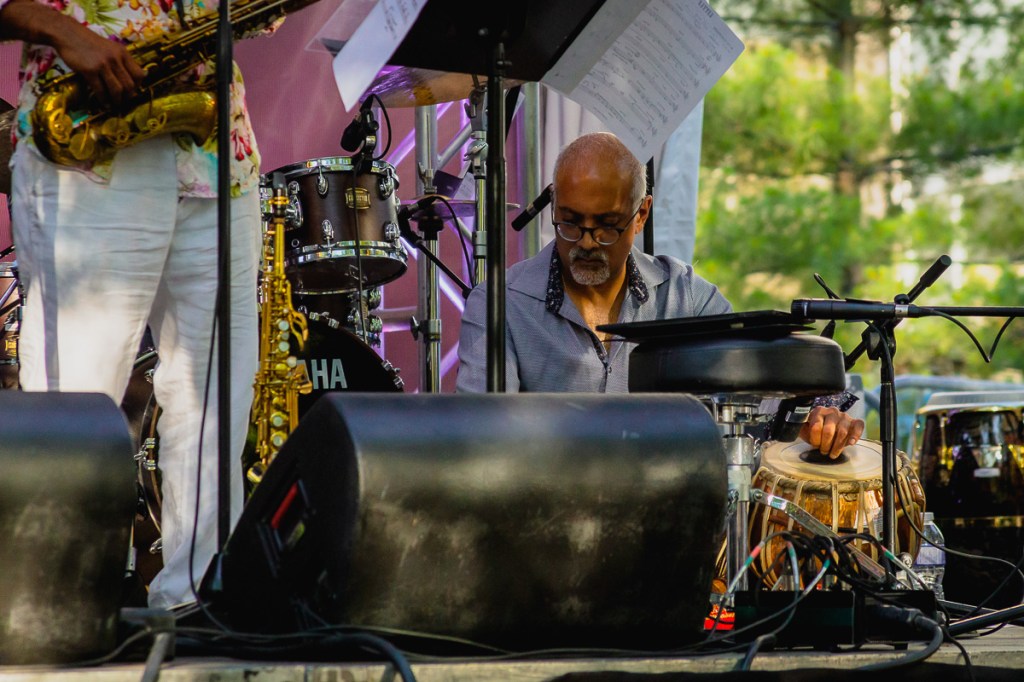 A brown man plays tabla on an outdoor concert stage. © Andy Lee, 2022. realandylee.com