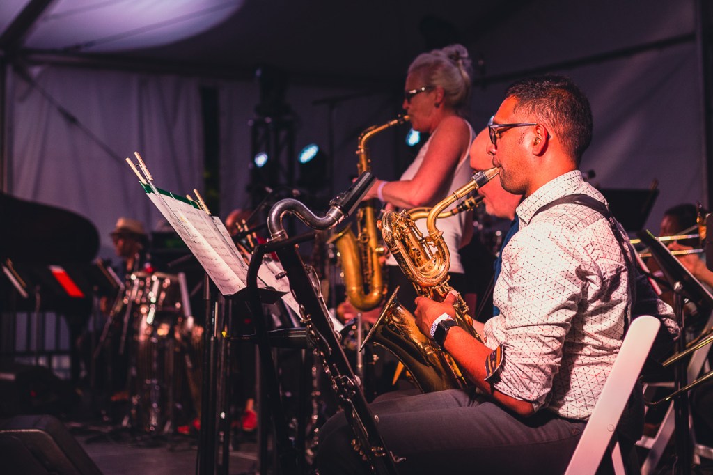 Two men and a women play saxophone as part of a big jazz band. © Andy Lee, 2022. realandylee.com