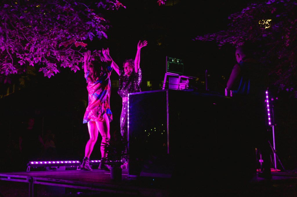 A man and woman jump up on an outdoor stage at night. © Andy Lee, 2022. realandylee.com