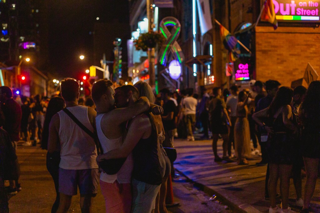 A gay couple kisses on the street during Toronto Pride. © Andy Lee, 2022. realandylee.com
