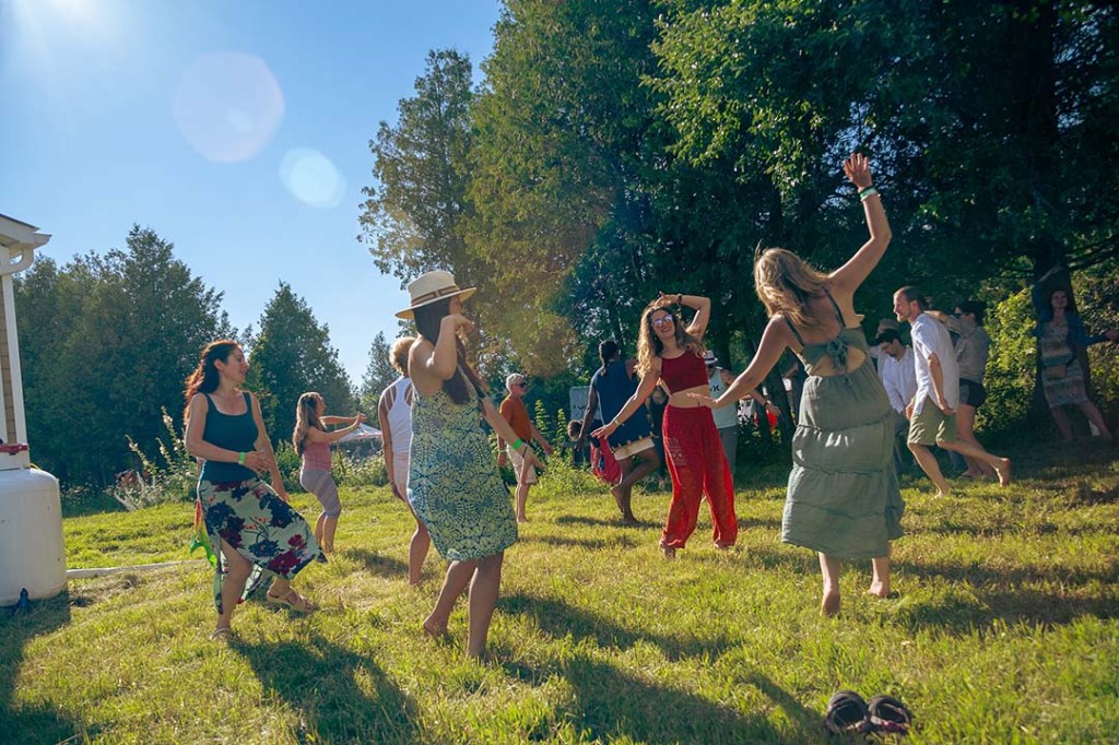Women and men dancing in nature with sun shining