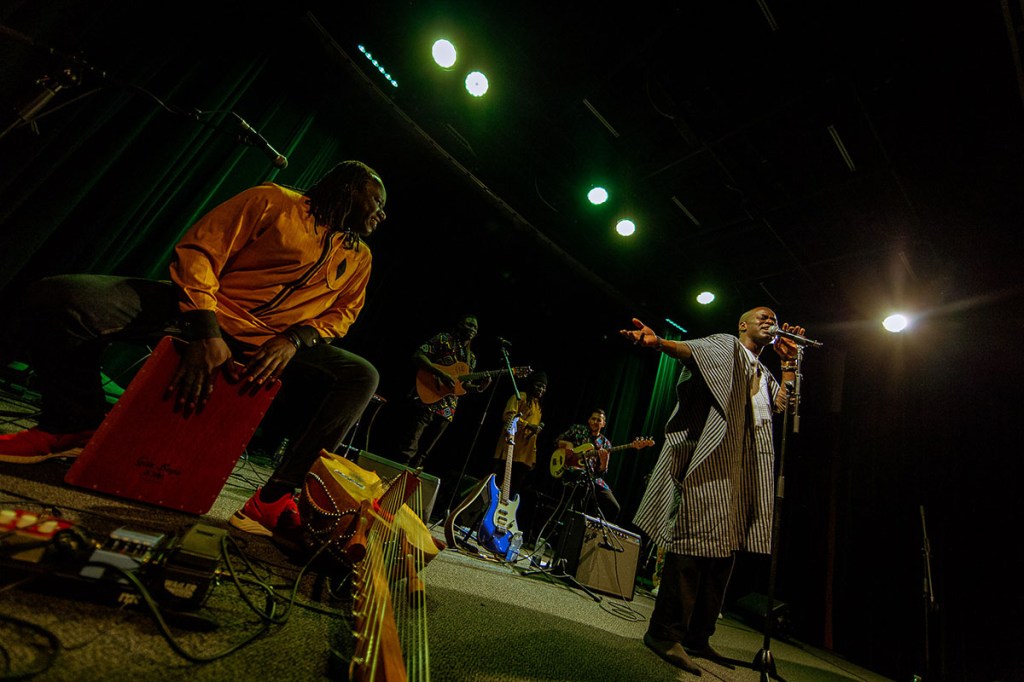 Seydina Ndiaye sings as Sadio Sissokho smiles and plays cajon