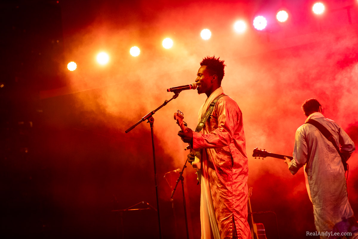Guitarists in long robes play onstage with colourful smoke