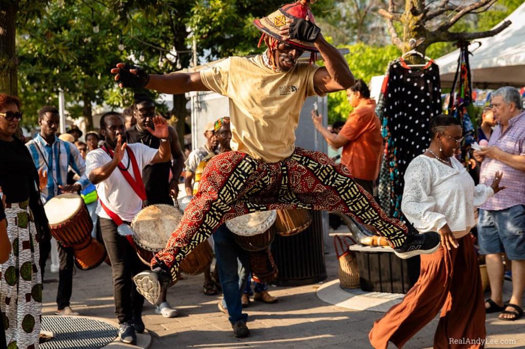 Black acrobat spread eagles while holding his hat during parade