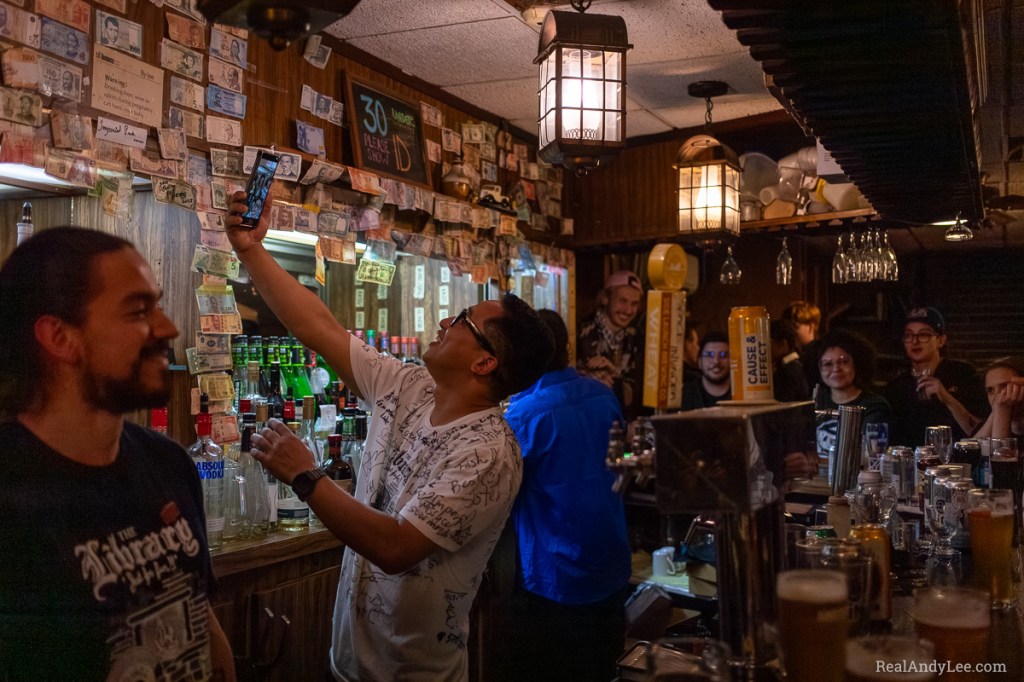 A bartender takes a selfie with patrons at the Imperial Pub