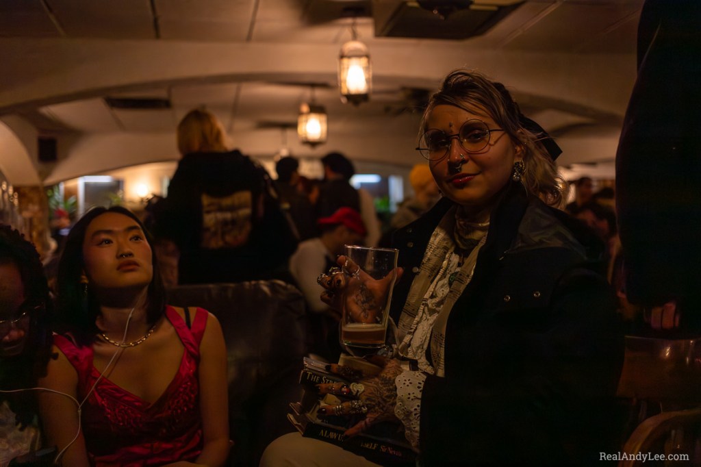 Blonde woman with glasses, piercings and tattooed hands drinking a pint inside the Imperial Pub