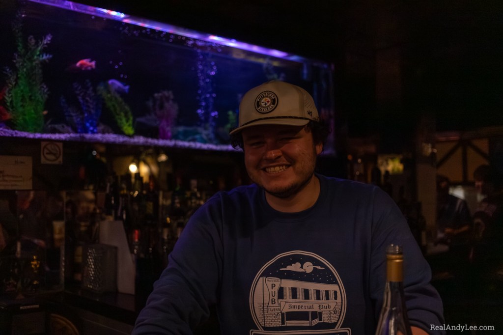 Smiling bartender with aquarium and liquor bottles behind him