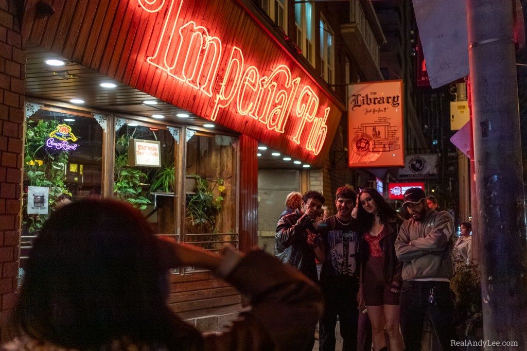 Bar patrons posing for a group photo outside the Imperial Pub at night